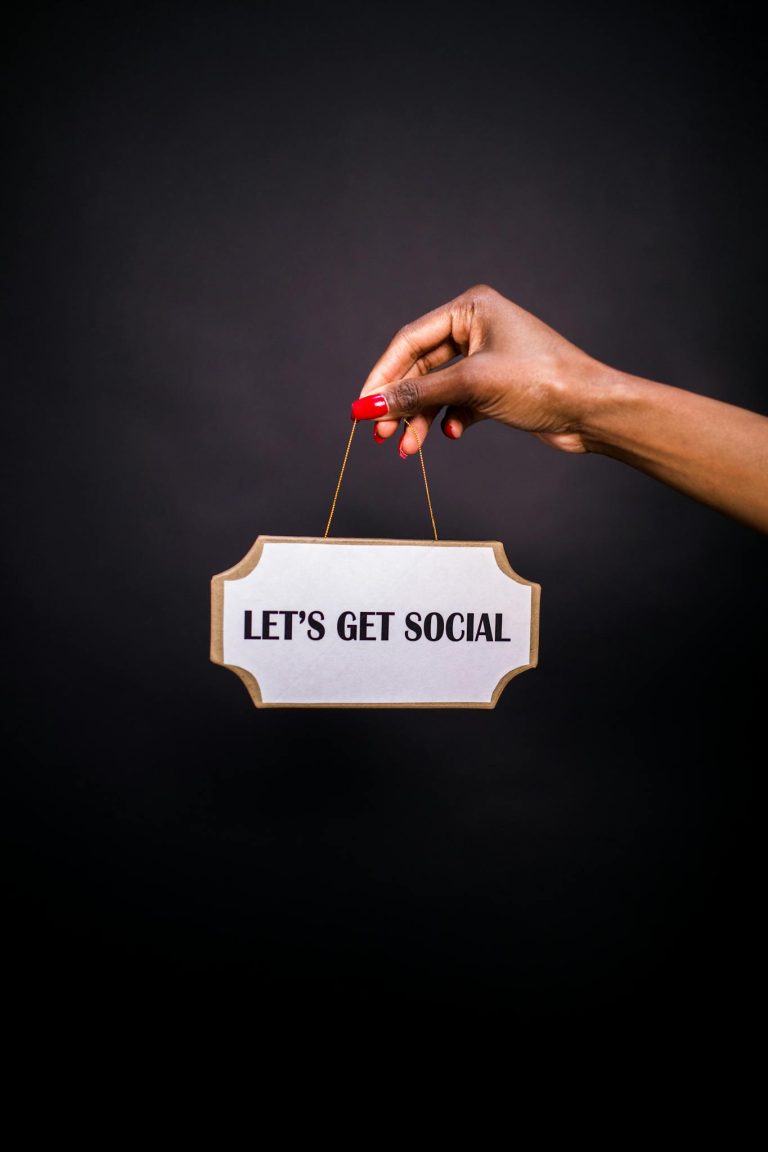 Crafting the Perfect Blog Structure: A Guide for Effective Blogging 3 Close-up of a hand holding a sign with 'Let's Get Social' on a dark background.